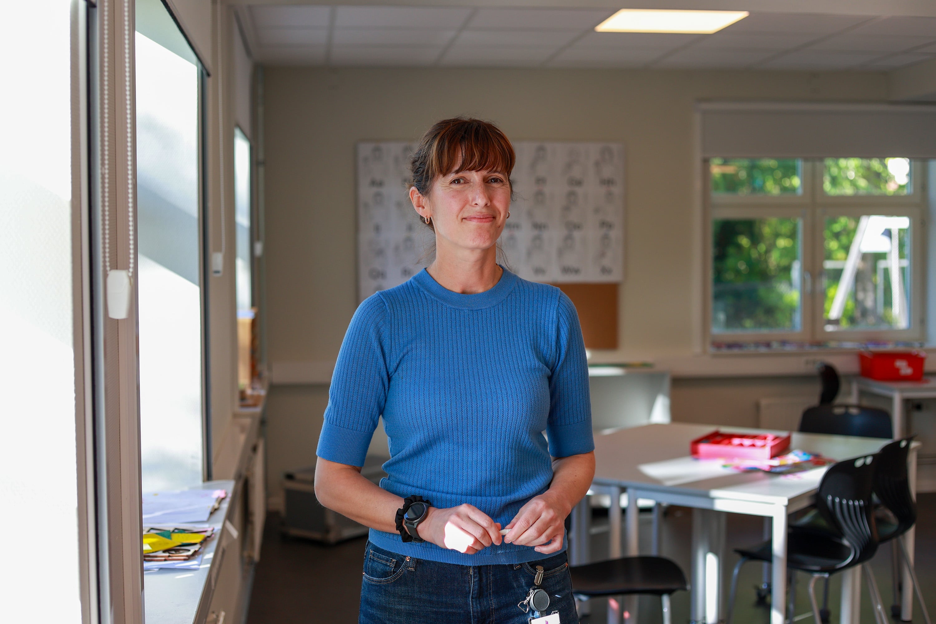 Elvira smiler til kamera. Bak henne skimter vi et klasserom.